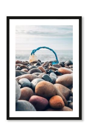 Plastic waste and blue rope on a pebble beach highlighting pollution