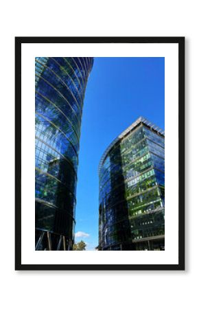 Modern skyscrapers and lush trees against blue sky, double exposure. Low angle view