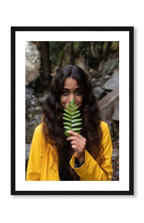 Close-up of young woman holding leaves while standing in forest