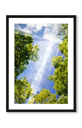 green city - double exposure of lush green forest and modern skyscrapers windows.