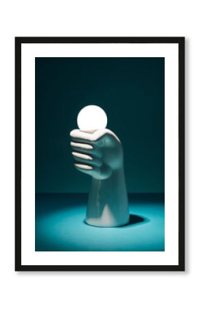 Concrete hand holding a light bulb on a dark background. Electricity, power minimal concept.