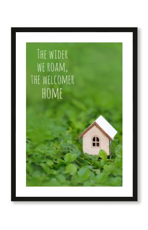 The wider we roam, the welcomer home - text and toy wooden house on green grass background. Symbol of happiness, family, Mortgage, Real estate concept. Eco Friendly House. Home sweet home. soft focus