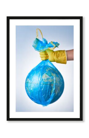 The concept of protecting the world from plastic waste, fighting environmental pollution, a hand in a yellow rubber glove holds a blue garbage bag with a globe on a light background.