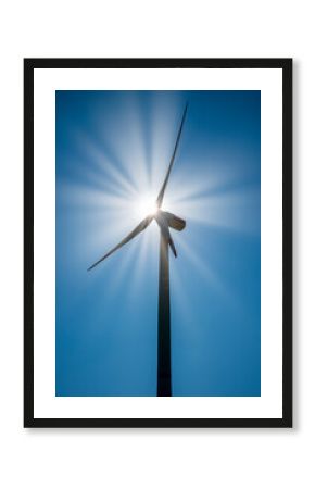 Wind turbine with sunbeams in a clear blue sky