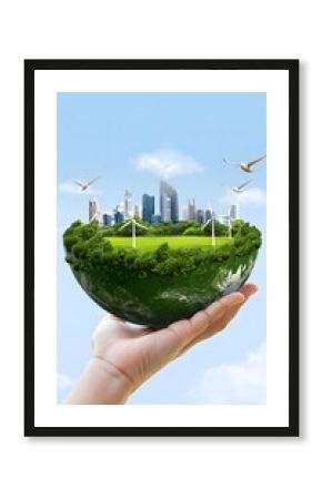Earth globe with city and windmills held in hand against sky