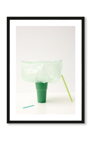 Emerald-green cup, light green straw and plastic bag with piece of tape
