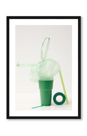 Emerald-green cup, tape, light green straw and plastic bag installation