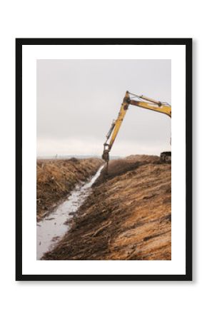 An excavator drips earth near a reclamation canal.