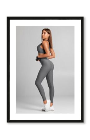 Sexy fitness woman. Beautiful athletic girl on the gray background