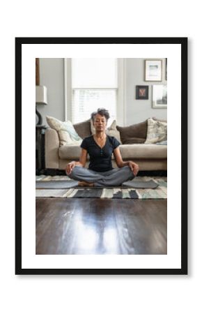 Black mom meditates in family room, teenage son on phone in background, peaceful health  and wellness