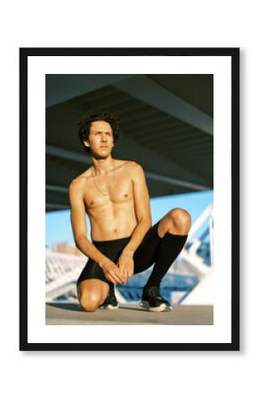 Shirtless man kneeling on street