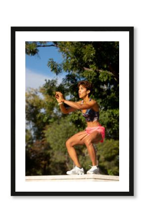 Muscular Hispanic sportswoman doing squats in park