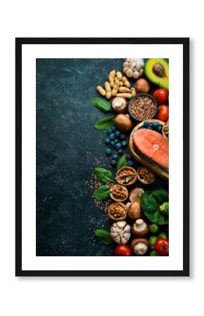 Heart health foods: salmon, avocados, blueberries, broccoli, nuts and mushrooms. On a black stone background. Top view. Copy space.