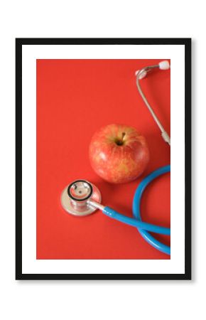 an apple and a medical stethoscope on a bright red background