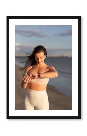 Fit Woman Looks At Her Watch On The Beach