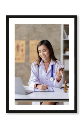 Asian female doctor sitting at a hospital desk, giving health care and disease prevention advice, convenient online services to patients and smiling, writing prescriptions to order medicine.