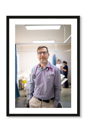 Smiling middle-aged male doctor  with a stethoscope around his  neck standing in the clinic