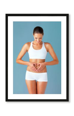 Heart, hands on abdomen and woman with gut health and wellness isolated on blue background. Weight loss, fitness and healthy female person with self love and body care in studio with diet