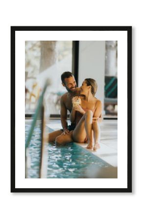 Young couple relaxing by the indoor swimming pool