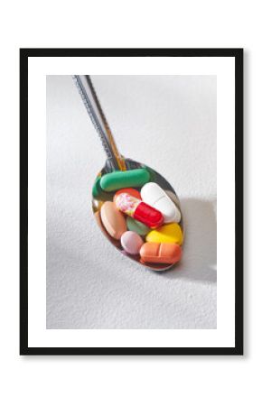 Spoon of colorful pills on white