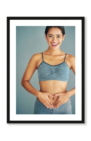 Woman, stomach and heart in studio portrait, gut health and symbol for colon wellness on blue background. Female person, hands and abdomen for digestion, love emoji and detox for progress in fitness