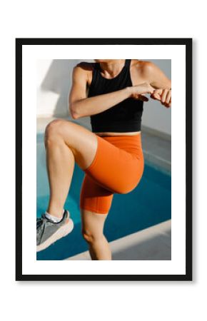 An unidentified fitness woman does aerobic workout next to a pool