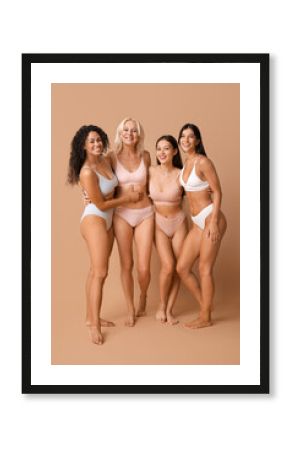 Beautiful different happy body positive women hugging on beige background