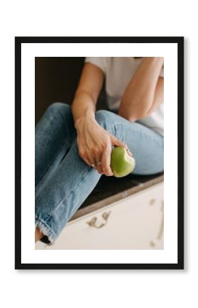 Close up of a woman holding a green bitten apple.