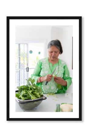 Senior South Asian woman in a kitchen preparing vegetables.