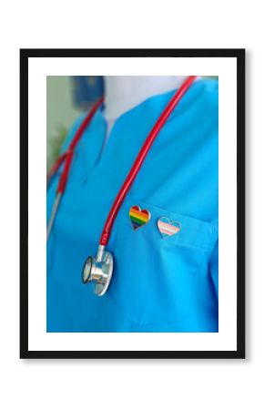 Scrubs in vibrant blue feature heart-shaped pins showcasing rainbow and transgender pride flags concept