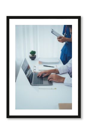 Doctor's Office: A dedicated medical professional meticulously working on a laptop while consulting records, epitomizing precision and commitment in a healthcare environment. 