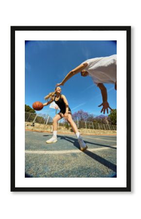 Girl dribbles basketball while being challenged by a boy outdoor