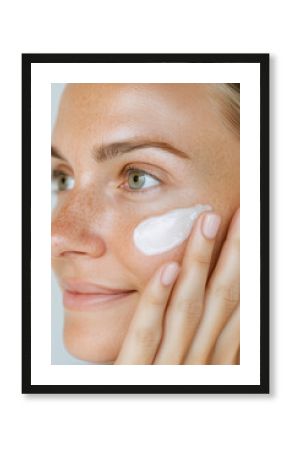 Close-up portrait of a woman applying moisturizer to her face showcasing bright skin highlighting skin care, Cream Smear, sun protection, natural beauty, and rejuvenation concept