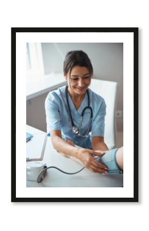 Joyful female doctor checking patient blood pressure in clinic