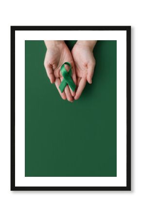 World bipolar day. Adult hands holding green ribbon. Mental health awareness day, Depression, Cerebral palsy. World kidney day.