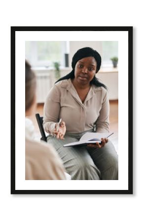 Confident psychotherapist in casualwear giving advice to young female patient at psychological session while sitting in front of her