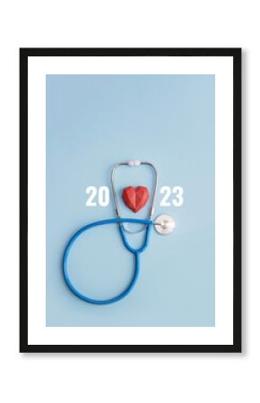 Stethoscope, polydiagonal decorative heart and numbers 2023 on blue background. Vertical medical banner or postcard for clinic. Selective focus, copy space