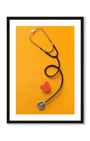 Stethoscope and red heart on yellow background. Cardiology concept