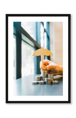 Model of umbrella and coins on wooden table concept of the system of insurance savings and the cost of health insurance