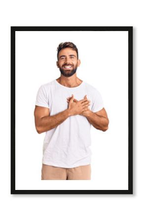 Young hispanic man wearing casual white tshirt smiling with hands on chest with closed eyes and grateful gesture on face. health concept.