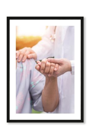 Elderly senior dementia patient (aging old adult person) in nursing hospice home holding geriatrician doctor's hand having happy medical health care from hospital carer or caregiver healthcare service