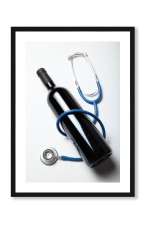 Glass bottle of red wine and stethoscope. Prevention of heart disease.