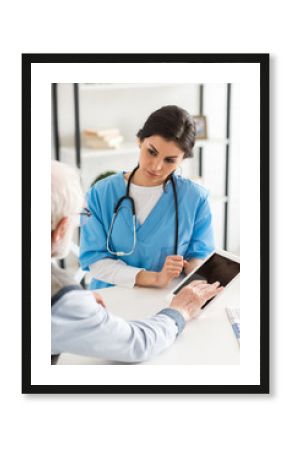 Cropped view of retired man sitting near doctor, and using digital tablet