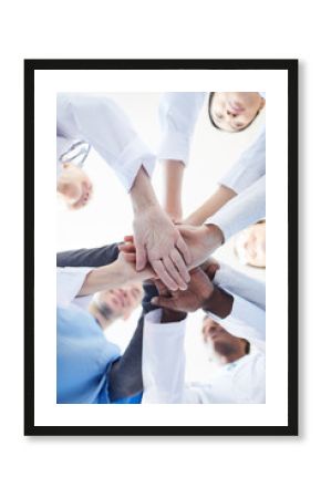 Directly below view at multi-ethnic group of doctors stacking hands in team building exercise