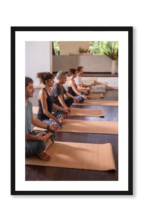 Diverse group of people on wooden floor practicing yoga- sitting and meditating in lotus pose. Healthy lifestyle and wellness