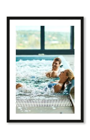 Happy couple relaxing during water massage in swimming pool at wellness.