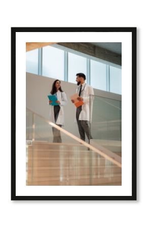 Doctors walking and discussing medical records in hospital corridor