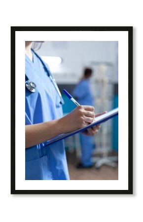 Close-up shot of nurse writing on clipboard, filling medical form in clinic