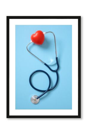 Red heart and stethoscope on blue background. Heart health and care concept.