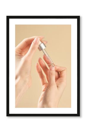 A woman applies nail care liquid to the skin with a pipette.